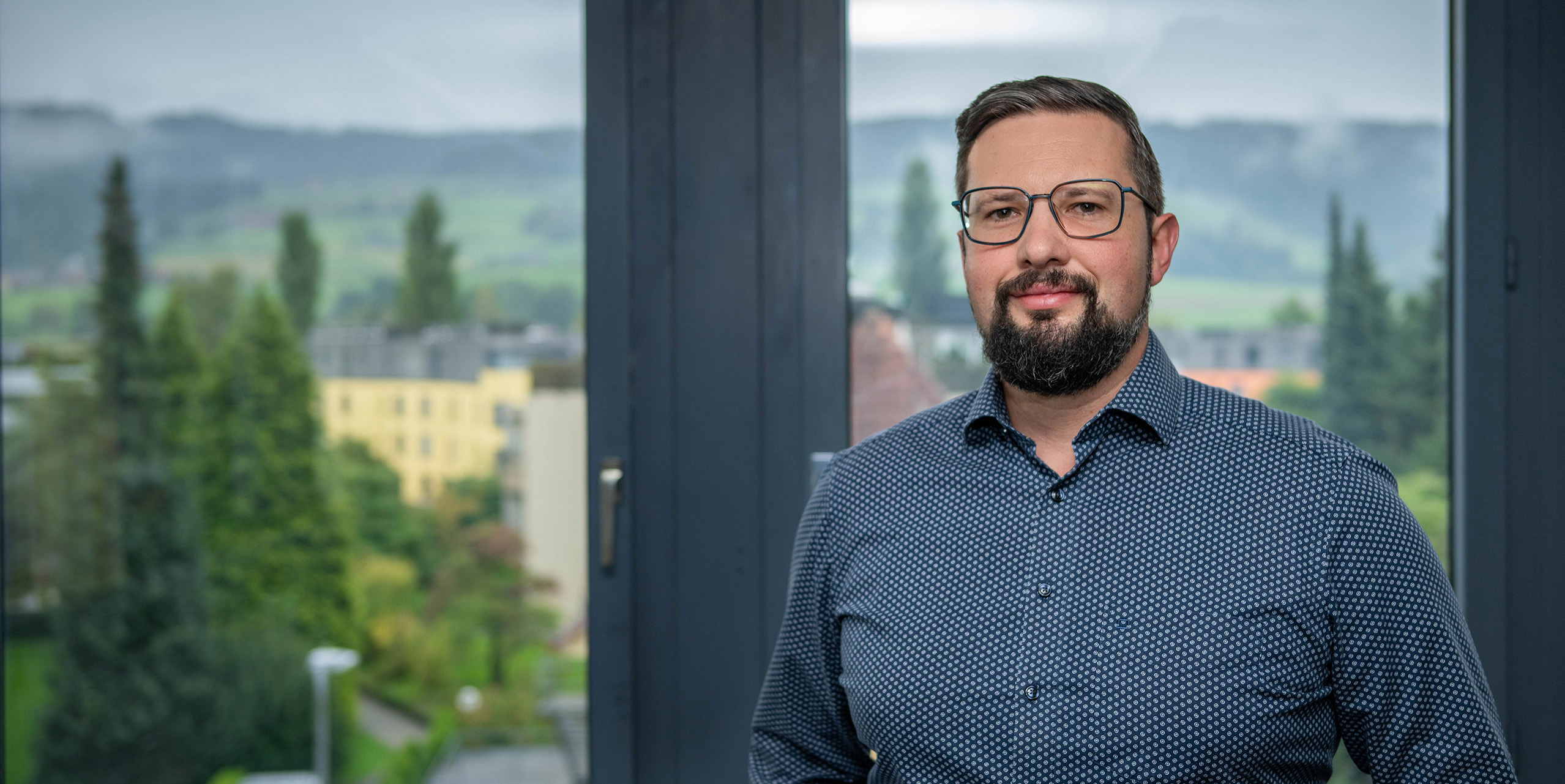 Kundenberater mit Brille und blauem Hemd schaut freundlich.