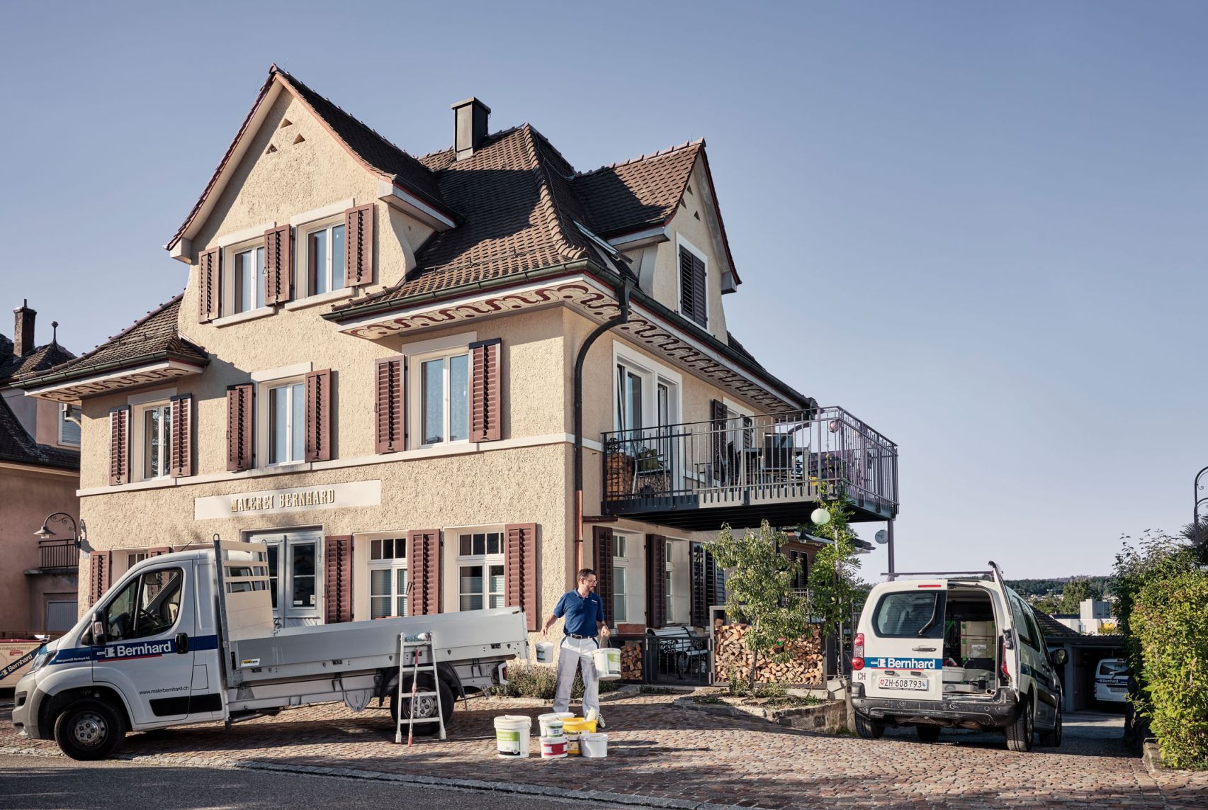 Das Geschäftsgebäude eines Malereigeschäfts von aussen fotografiert. Davor steht ein Klein-Lastwagen, der von einem Mitarbeitenden entladen wird.