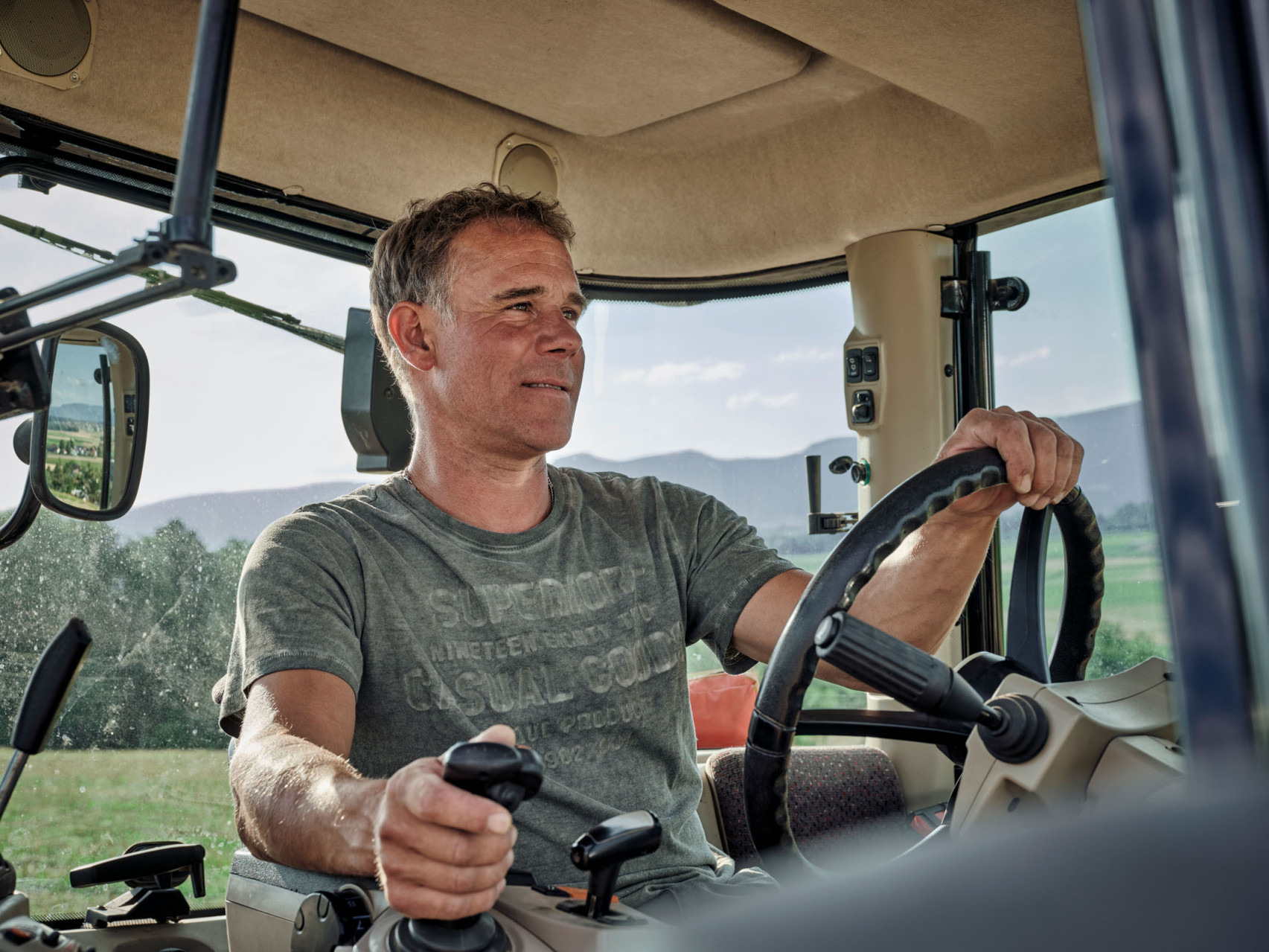 Ein Bauer sitz am Steuer seines Traktors und fährt über seinen Acker.