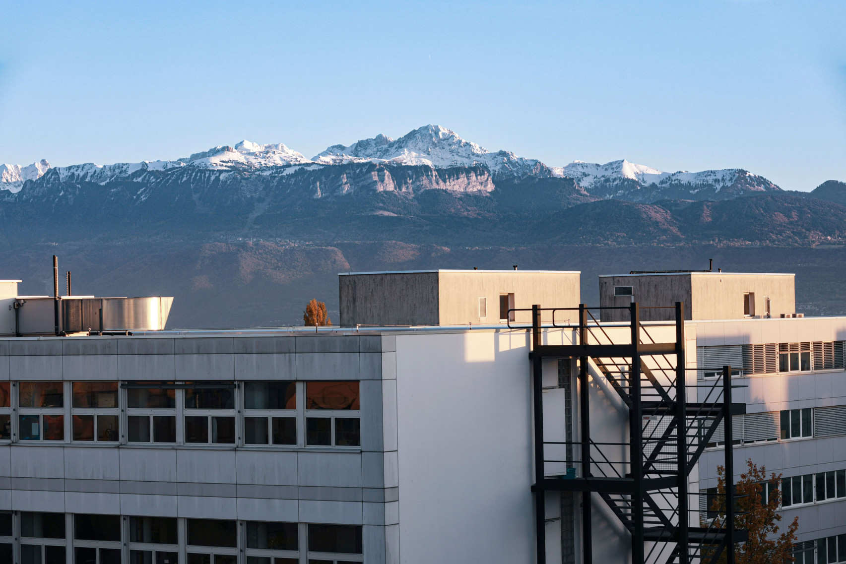 Das Dach eines Firmengebäudes mit einer gebirgigen Landschaft im Hintergrund.