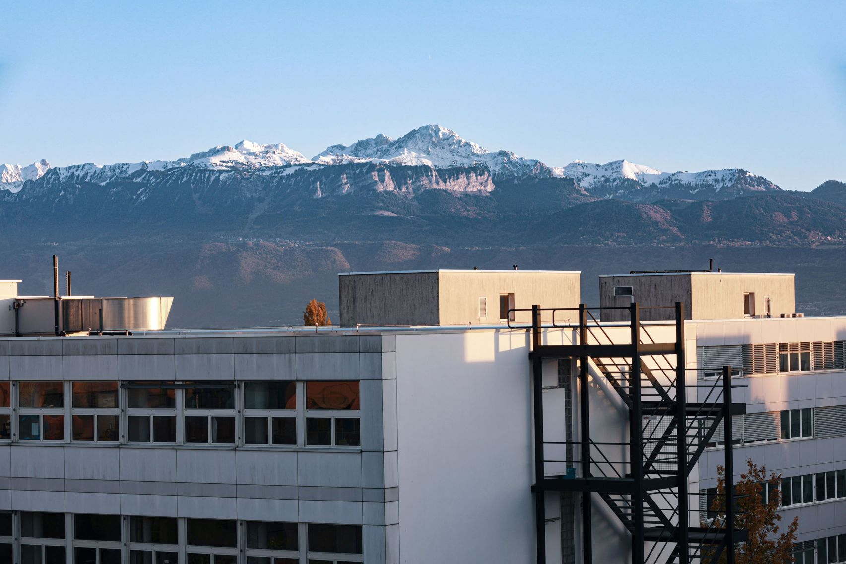 Das Dach eines Firmengebäudes mit einer gebirgigen Landschaft im Hintergrund.
