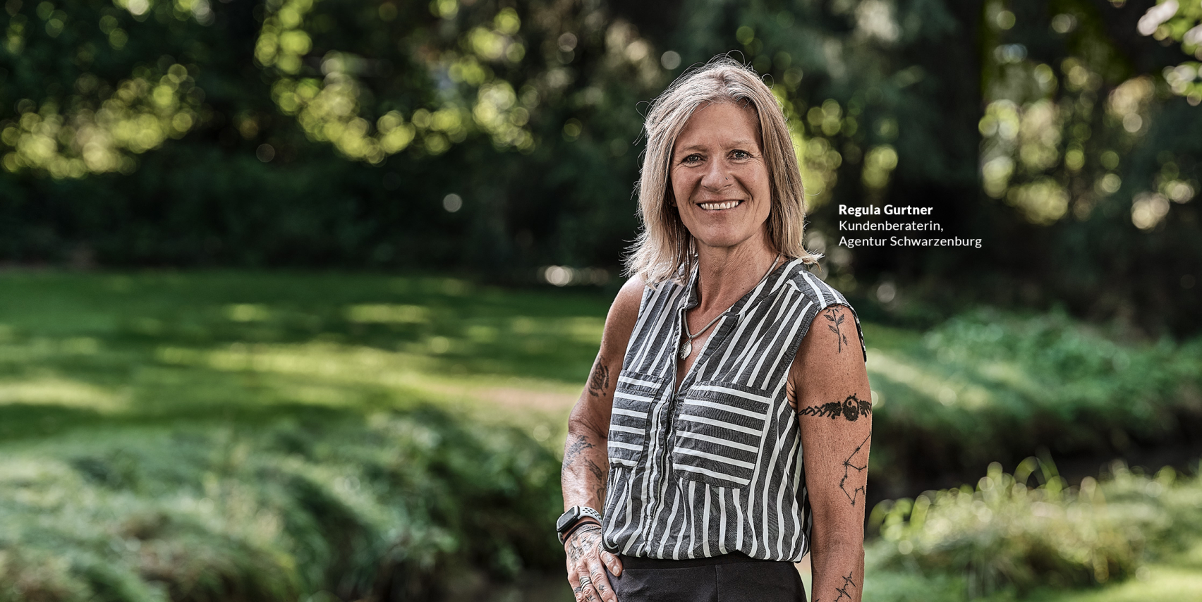 Eine Kundenberaterin der emmental versicherung steht draussen in einem begrünten Park und blickt freundlich in die Kamera.