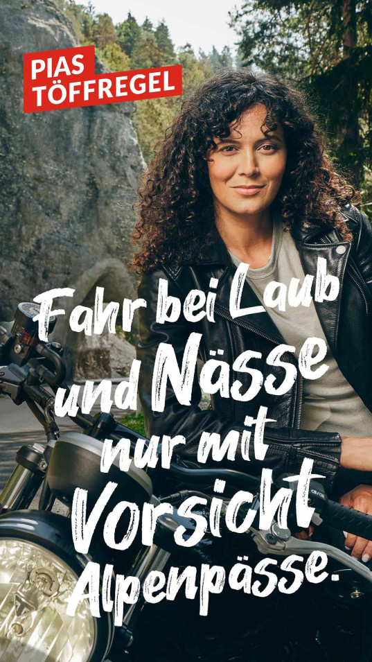 Eine junge Frau steht lehnt sich stehend an Ihr Motorrad vor einer herbstlichen Kulisse. Das Bild enthält einen Werbeslogan.